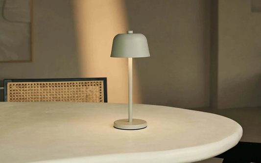 Oplaadbare tafellamp op een ronde eettafel met rotan stoelen